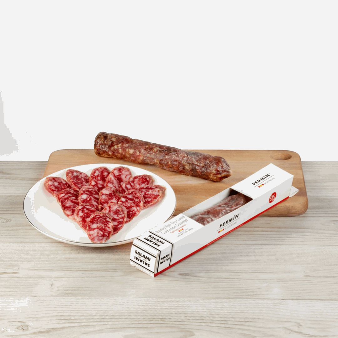 piece of Dry-cured Salchichon Iberico Fermin and some slices on a table