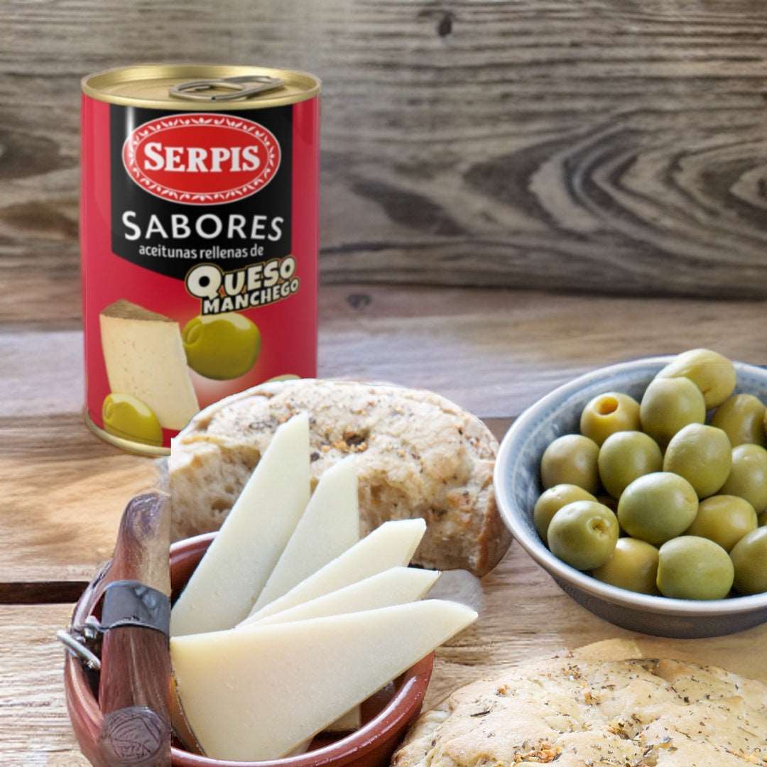 a bowl with green olives and some pieces of cheese