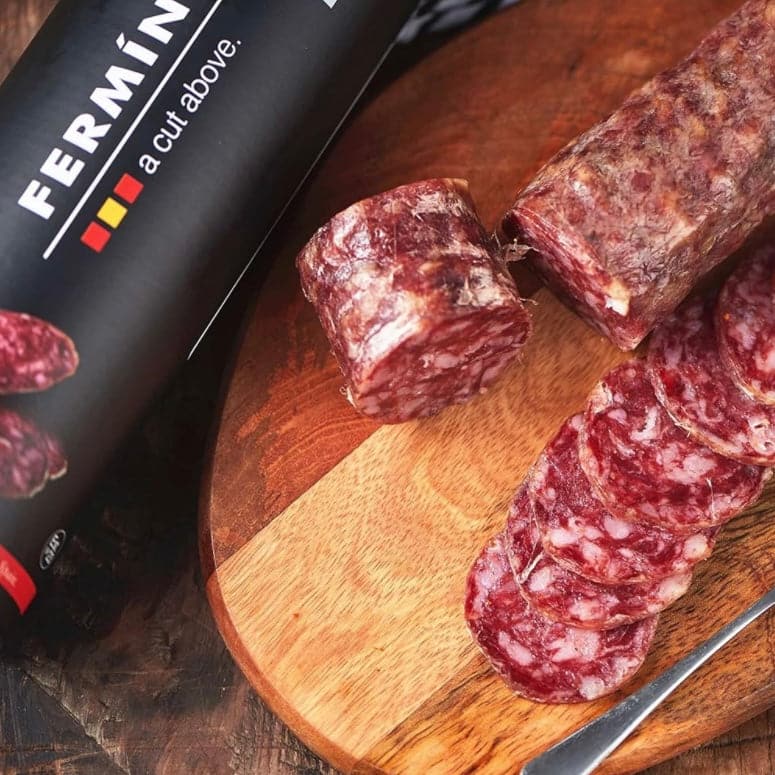 Slices of Salchichón Ibérico Bellota by Fermin on a wooden board